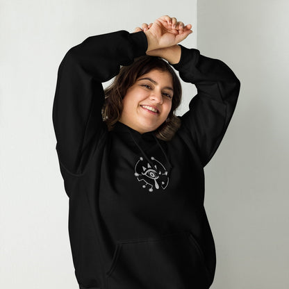 A person wearing a black Zelda Sheikah Eye embroidery hoodie smiles while raising their arms.