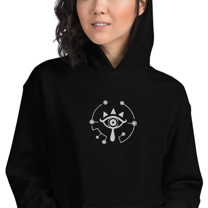 A person wearing a black hoodie featuring an embroidered Sheikah Eye design inspired by The Legend of Zelda: Breath of the Wild and Tears of the Kingdom.