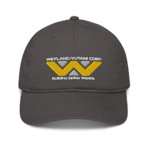 A gray baseball cap features an embroidered Weyland-Yutani Corp logo with yellow and white geometric shapes and the words "Building Better Worlds.
