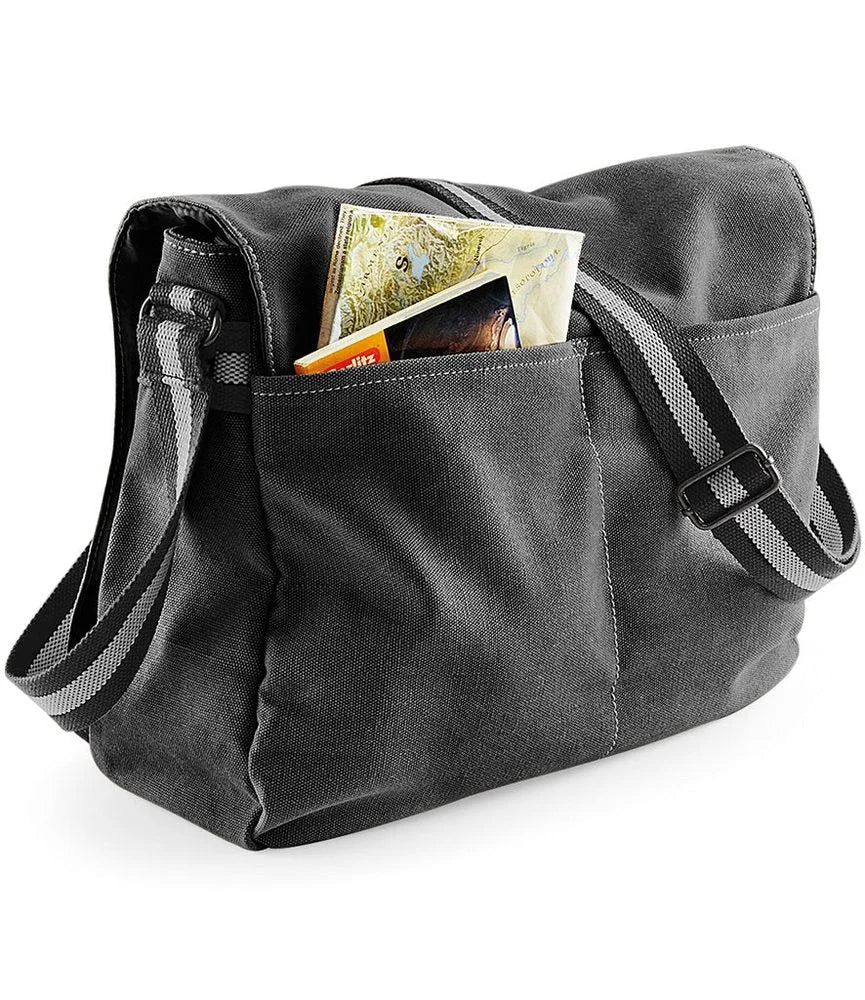 A dark grey canvas messenger bag featuring a pocket containing papers and an adjustable shoulder strap.